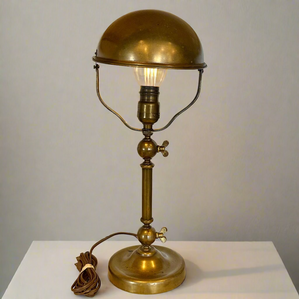 Brass table lamp with a light bulb on a white surface and gray background