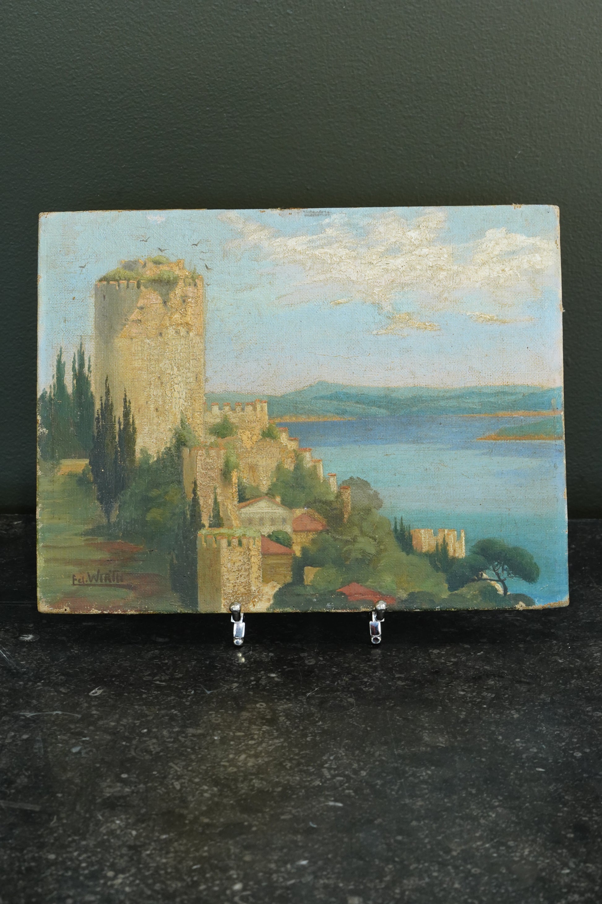 Painting of a castle by a lake on a dark surface