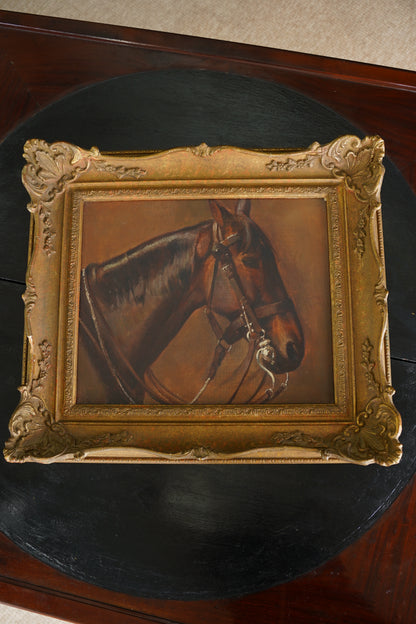 A framed oil painting of a brown horse's head in profile, set in an ornate gold frame, displayed on a dark round table.